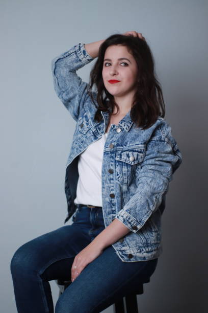 istock attractive brunette in jeans and denim jacket on grey background. studio shoot 1283731717