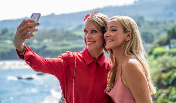 duas lindas mulheres, vestidas elegantemente, fazem uma selfie, em frente a um esplêndido panorama. - political party concepts glamour friendship - fotografias e filmes do acervo
