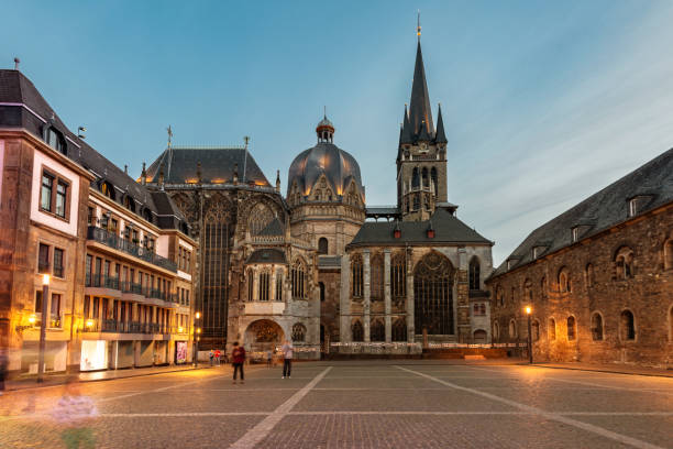 low angle view on Katschhof in Aachen with Cathedral at blue hour low angle view on illuminated Katschhof in Aachen with Cathedral at blue hour, only view people walking aachen photos stock pictures, royalty-free photos & images