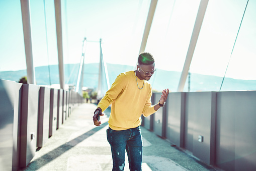 African Male Dancing On Bridge Outside While Enjoying Music