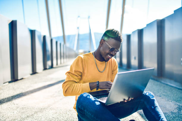 istock African Male Enjoying Using Laptop Outside On Bridge During Sunny Day 1283735943