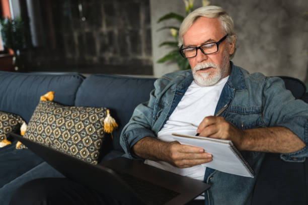 Elderly professor conduct online lesson using laptop computer Senior man speak talk on video call while Sitting on sofa
