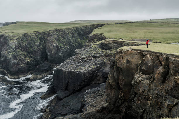 istock Tourist admires the waves crashing against the cliffs 1283736108