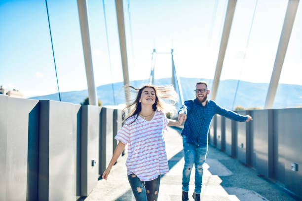 istock Female Dragging Her Boyfriend With Her On A Walk Across Bridge 1283736121