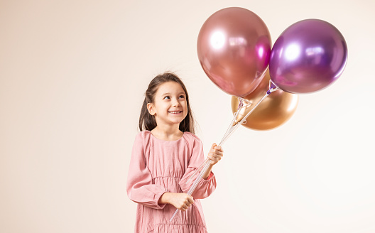 Girl is looking and holding balloons.