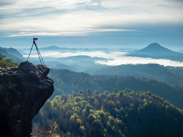 istock Camera on tripod photographing mist in valley 1283740837