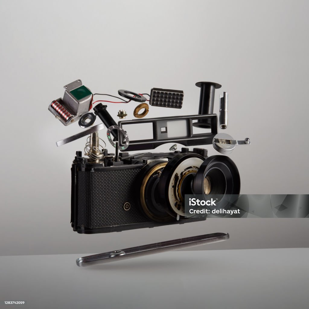 Parts and components of a disassembled analog vintage film camera floating in the air on white background Camera - Photographic Equipment Stock Photo