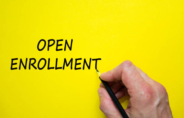 istock Hand writing 'open enrollment', isolated on beautiful yellow background. Concept. Copy space. 1283744117