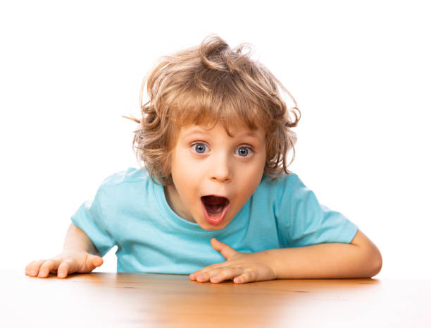 4 years old happy child by the table Portrait of four years old child sitting by the table. He is suprised little boys blue eyes blond hair one person stock pictures, royalty-free photos & images