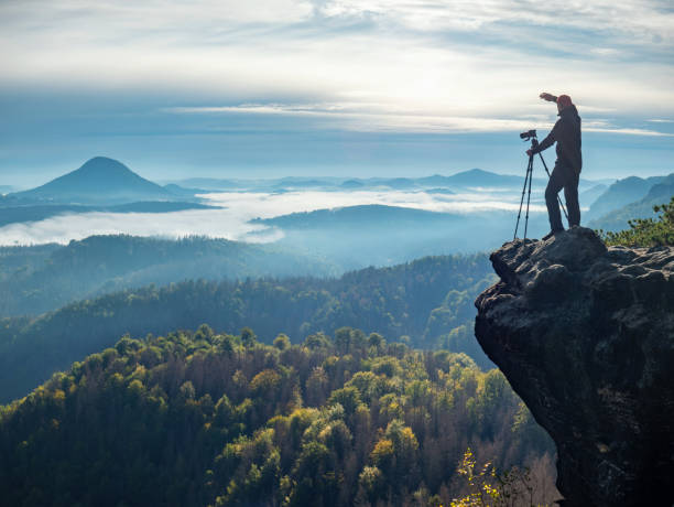 istock Professional on cliff. Nature photographer hold tripod with camera 1283744641