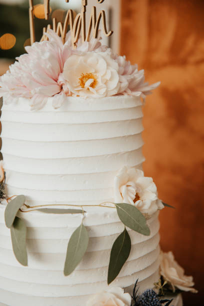 istock Three tiered wedding cake with eucalypus leaves and pink peonies, contemporary style 1283744734