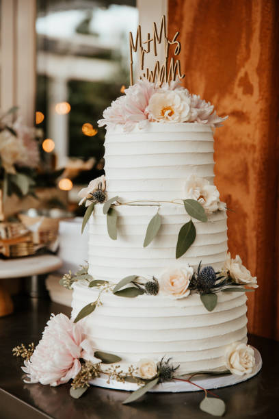 Three tiered wedding cake with eucalypus leaves and pink peonies, contemporary style Three tiered wedding cake with eucalypus leaves and pink peonies, contemporary style wedding cake stock pictures, royalty-free photos & images