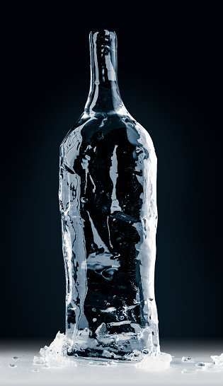 Bottle form, made of clean, transparent, natural ice on the reflective surface on black background. Purity and freshness concept.