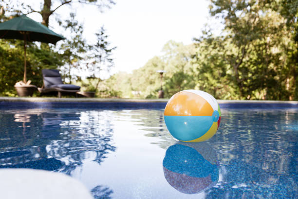 Friends playing with beach ball in swimming pool at home