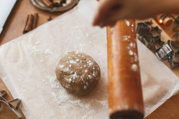 istock Hands pour flour for kneading raw gingerbread dough on rustic table. Making christmas cookies 1283747859