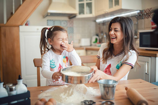 mother and daughter baking together with flour, they having time together at home.