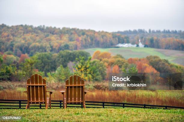 Empty Wooden Chairs In Autumn Fall Foliage Season Countryside At Charlottesville Winery Vineyard In Blue Ridge Mountains Of Virginia With Cloudy Sky Day Stock Photo - Download Image Now