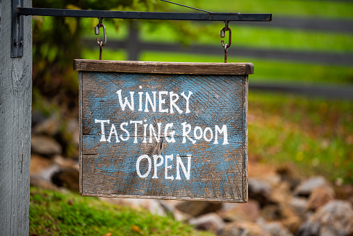 Closeup of Winery Tasting Room Open sign with bokeh background of grape vineyard winery farm landscape