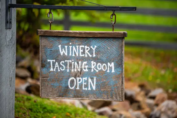 Photo of Closeup of Winery Tasting Room Open sign with bokeh background of grape vineyard winery farm landscape