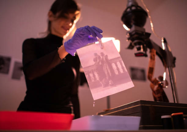 photographe féminine développant des photographies de film et d’impression dans le processus traditionnel dans la chambre noire. - photographer women retro revival camera photos et images de collection