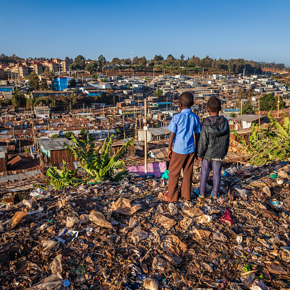 African children standing in trash and looking at houses in Kibera slum, Kenya, East Africa. Kibera is the largest slum in Nairobi, the largest urban slum in Africa, and the third largest in the world