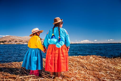 Madre y su hija mirando a la vista en la isla flotante de Uros, Lago Tititcaca, Perú photo