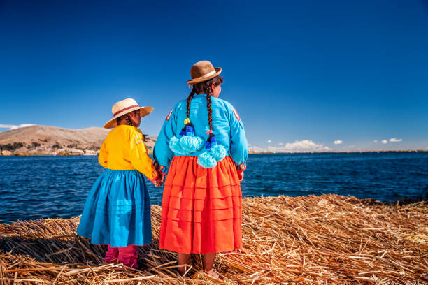 madre y su hija mirando a la vista en la isla flotante de uros, lago tititcaca, perú - trajes tipicos del peru fotografías e imágenes de stock