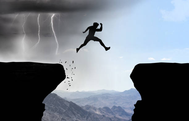 istock Man jumps over abyss with thunderstorm in background. 1283755020
