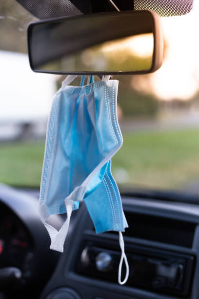 istock Surgical masks hanging on rear view mirrror in car 1283757216
