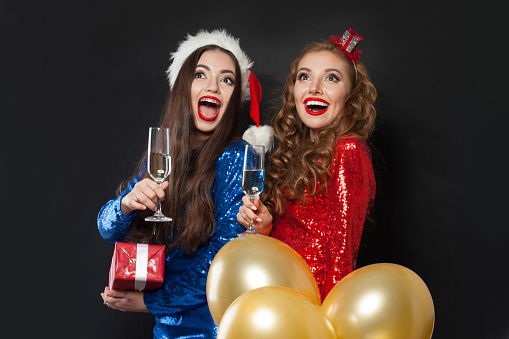 Christmas Portrait of two happy women laughing on black background