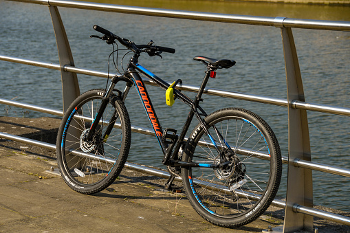 Swansea, Wales - July 2018: Bicycle left unattended against railings on the riverside walk. It is secured with a lock.