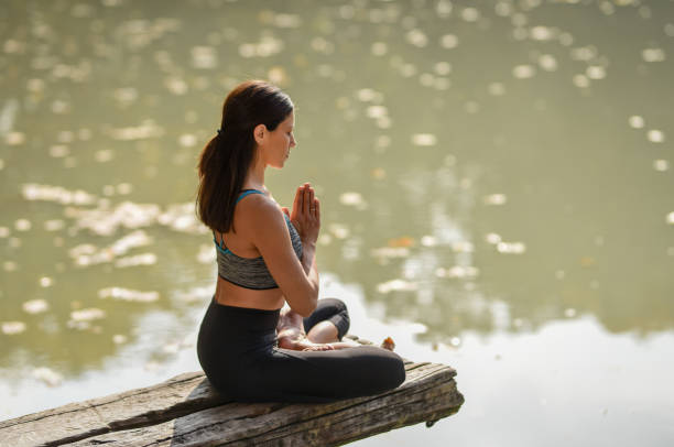 istock Young woman practicing yoga in nature by lake 1283758978