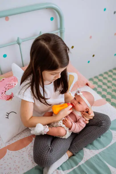 Photo of little girl playing feeding her baby doll