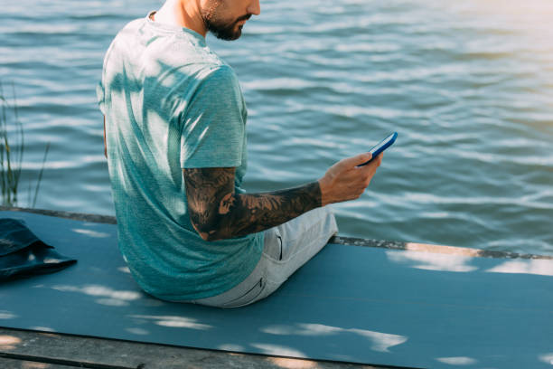 istock Anonymous Man Selecting an Online Yoga Class on his Mobile Phone Before Working Out Outdoors 1283760814