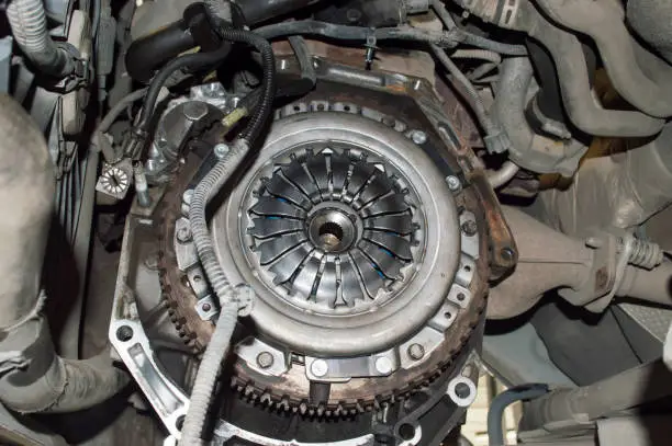 View of the engine compartment of the car from the side of the removed manual transmission. The clutch basket and the gear ring of the flywheel are visible