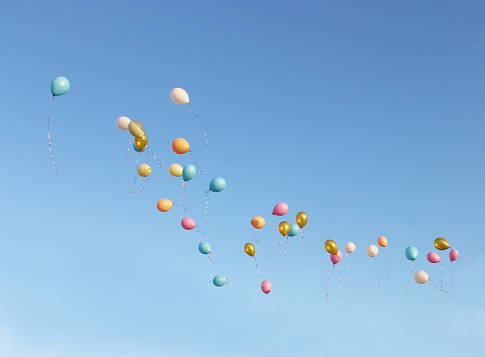 Colorful balloons soar into the blue sky on a Sunny day