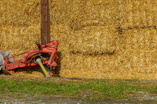 Hay in bales, folded under a canopy. Part of an agricultural machine.
