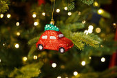 Toy shiny red car on the Christmas tree, holiday decor