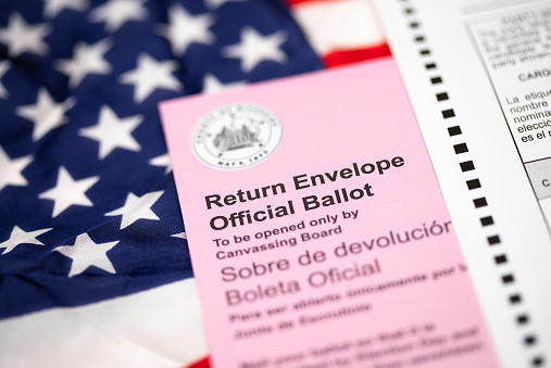 Vote-By-Mail Ballot Envelope Laying on American Flag.