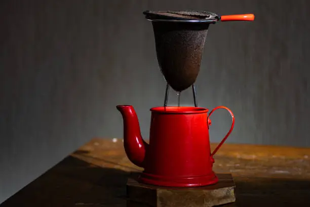 red coffee pot and cloth strainer, with dark background