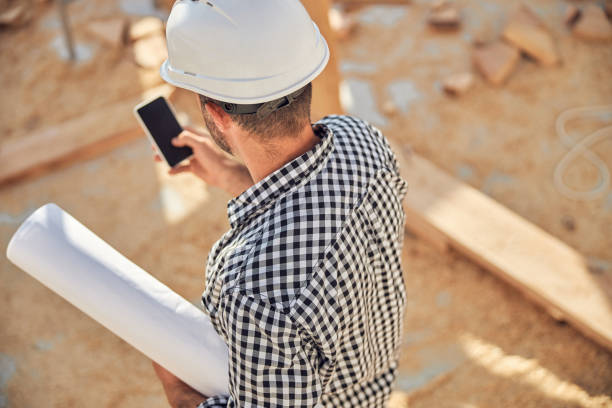 istock Busy architect with a roll of blueprints and a phone 1283773549
