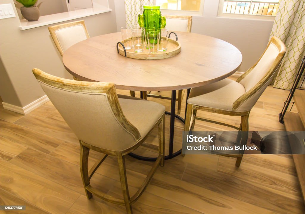 Dining Area With Round Wooden Table & Four Chairs Dining Area With Round Wooden Table, Centerpiece And Four High Back Chairs Baseboard Stock Photo