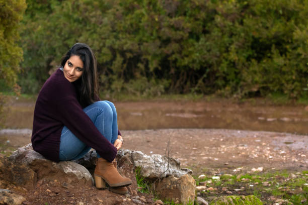 istock Pretty girl sitting on a rock and looking at camera 1283777930