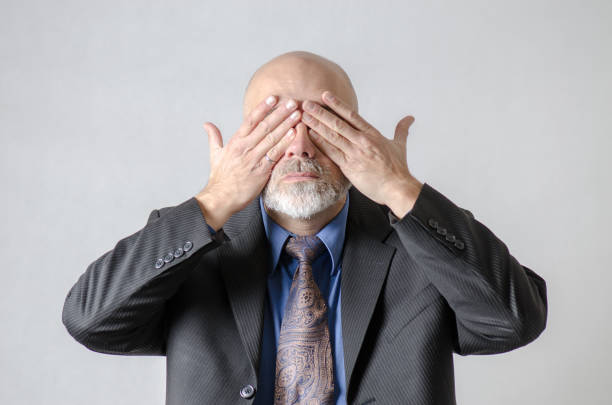 Business man covering his eyes with hands in studio with white background