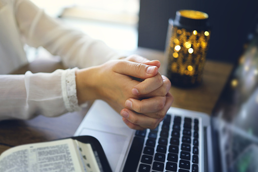 Woman praying by faith with computer laptop, Church services online concept, Online church at home concept, spirituality and religion.
