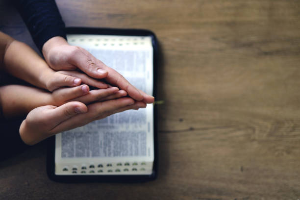 Religious Christian girl praying with her mother indoors Religious Christian girl praying with her mother indoors. Bible in background. Space for text religious cross photos stock pictures, royalty-free photos & images