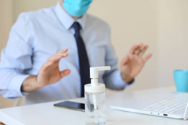 istock Coronavirus man wearing face mask using antiseptic bottle dispenser hand sanitizer alcohol gel hand wash to sanitize hygiene prevent corona virus health infection antibacterial during covid19 pandemic 1283783613
