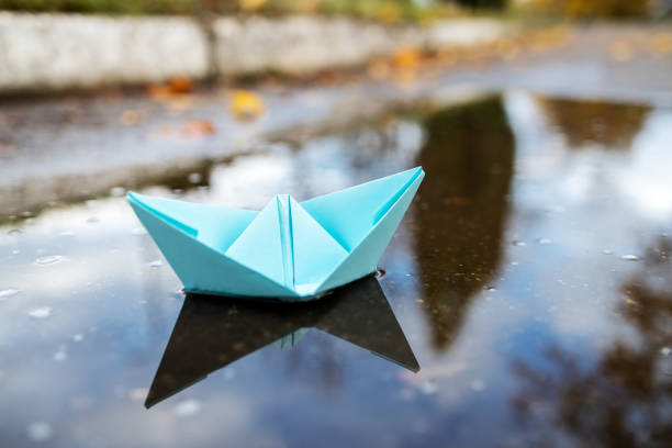 istock one blue paper ship floating on a water surface. outdoors. autumn season. greeting card with copy space. leadership conceptual. freedom concept 1283787213