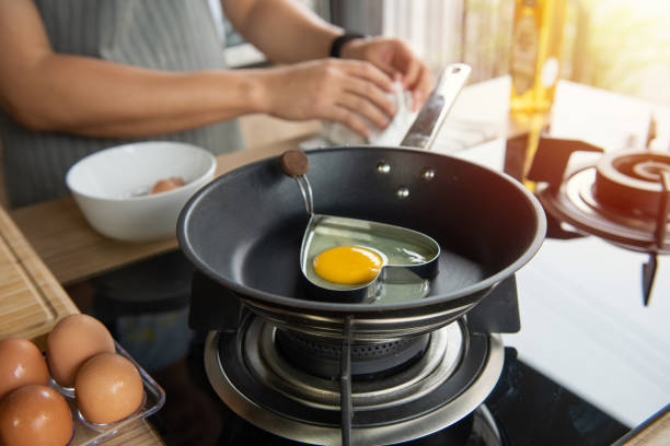 istock Hands breaking an egg into heart block in a pan 1283796020