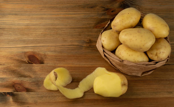 istock Raw Peeled Potatoes on Wooden Cutting Board Background 1283796748